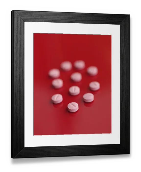 Framed Print : A striking image featuring several pink tablets casually dispersed on a saturated red backdrop