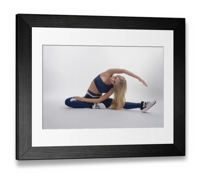 Framed Print : A woman showcases her impressive flexibility while stretching in a well-lit studio