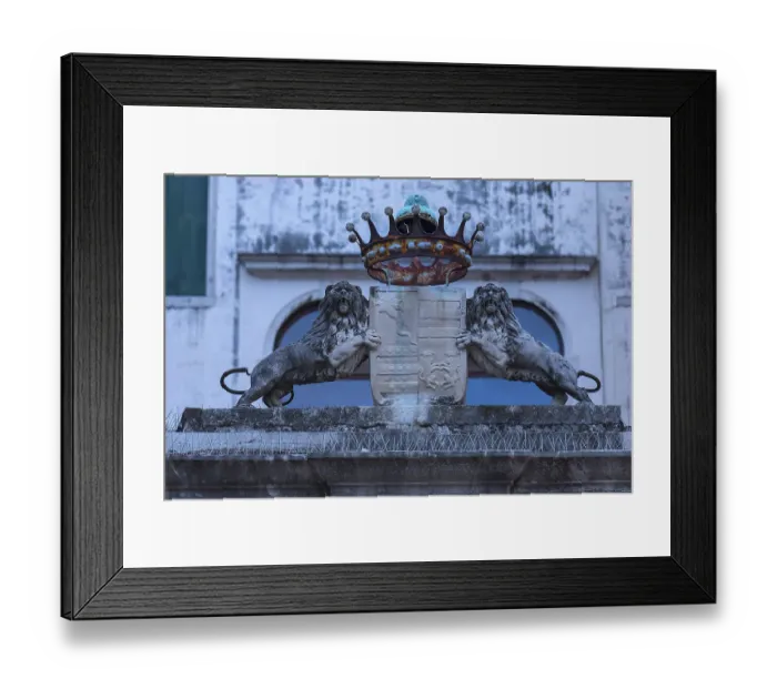 Framed Print : Two lion sculptures with a coat of arms and crown in front of a palazzo