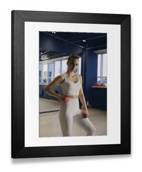Framed Print : A woman in a white sports outfit is lifting pink dumbbells in a bright gym