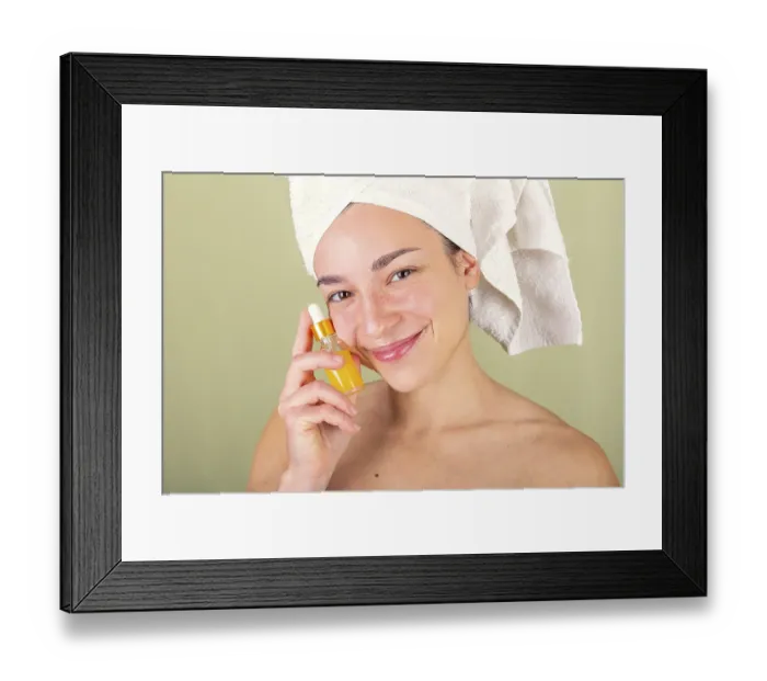 Framed Print : A woman with a towel wrapped around her head holds a small bottle of facial serum Framed Print : A woman with a towel wrapped around her head holds a small bottle of facial serum