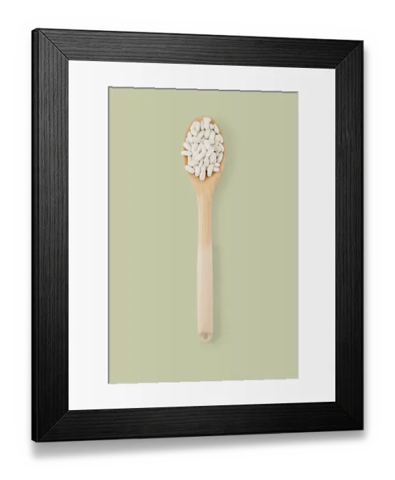 Framed Print : Top view of wooden spoon full of white beans on a green background