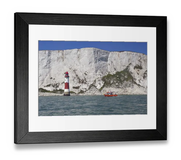 Framed Print : Red lighthouse and boat near white cliffs by the sea