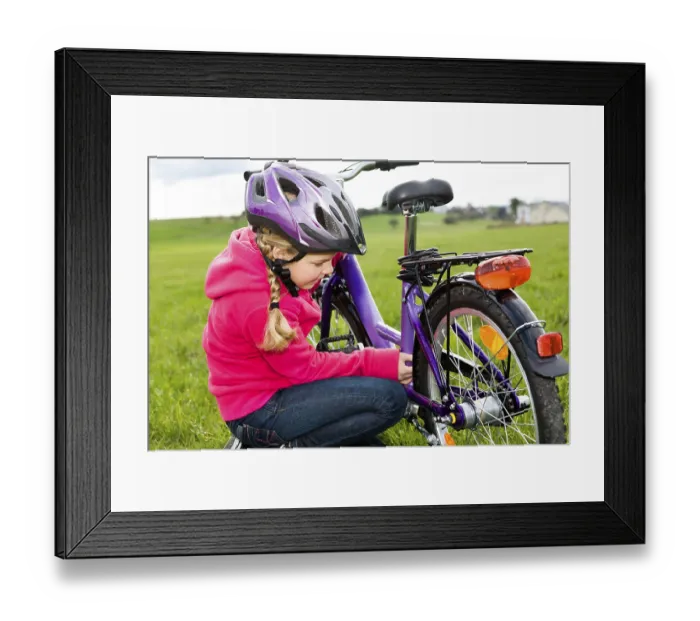 Framed Print : Girl wearing a cycling helmet, checking her bicycle Framed Print : Girl wearing a cycling helmet, checking her bicycle