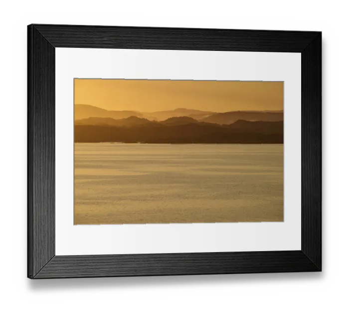 Framed Print : Calm atmosphere over the sea, hills and an orange sunrise