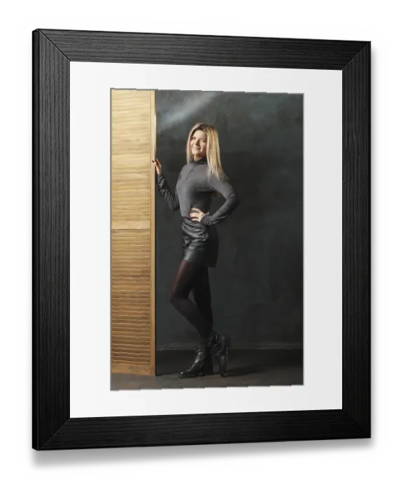 Framed Print : Cute girl in top, leather shorts and dense tights posing near folding screen