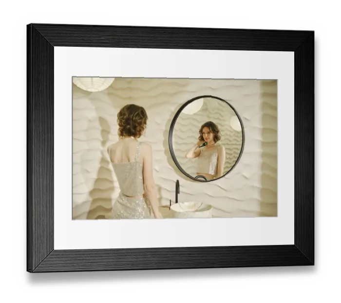 Framed Print : A woman dressed in a shimmering top stands in front of a round mirror