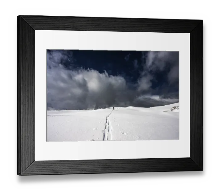 Framed Print : Ski tourer on a vast plateau with snow-covered mountains in the background and dramatic sky Framed Print : Ski tourer on a vast plateau with snow-covered mountains in the background and dramatic sky