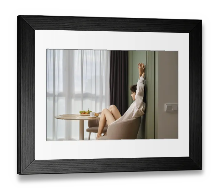 Framed Print : Young woman stretching while sitting at table in bright apartment Framed Print : Young woman stretching while sitting at table in bright apartment