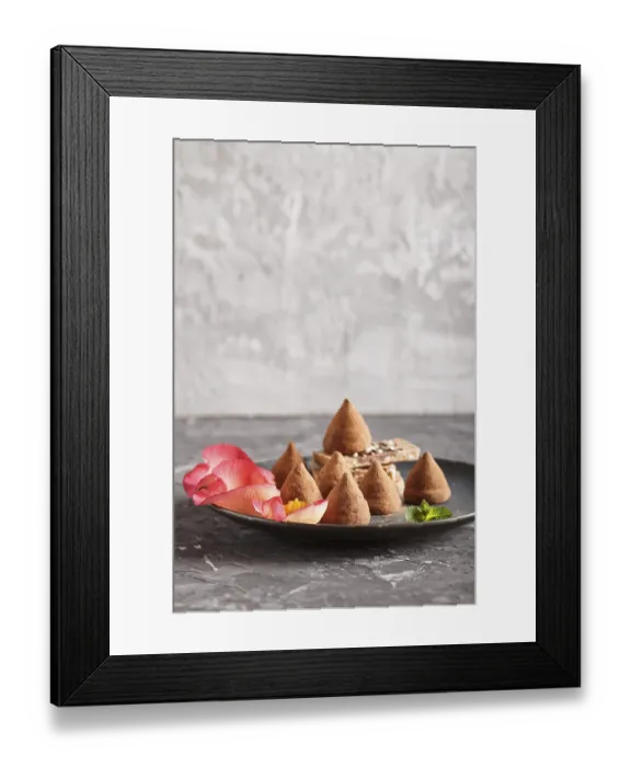 Framed Print : Chocolate truffle on blue ceramic plate decorated with rose petals on black concrete background