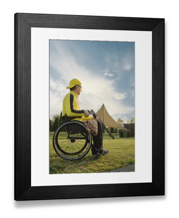 Framed Print : An elderly man with paralysed legs in a wheelchair opens his hunting rifle to reload the ammunition