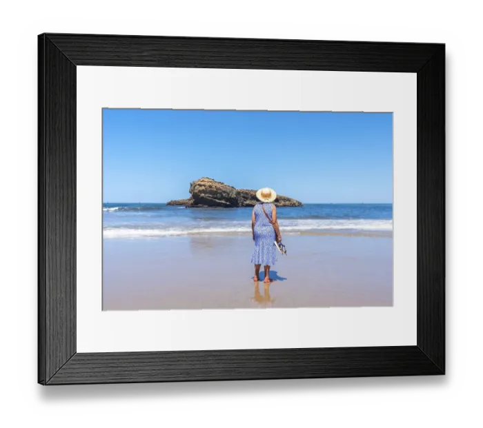 Framed Print : An elderly woman on vacation looking at the sea on the beach in Biarritz