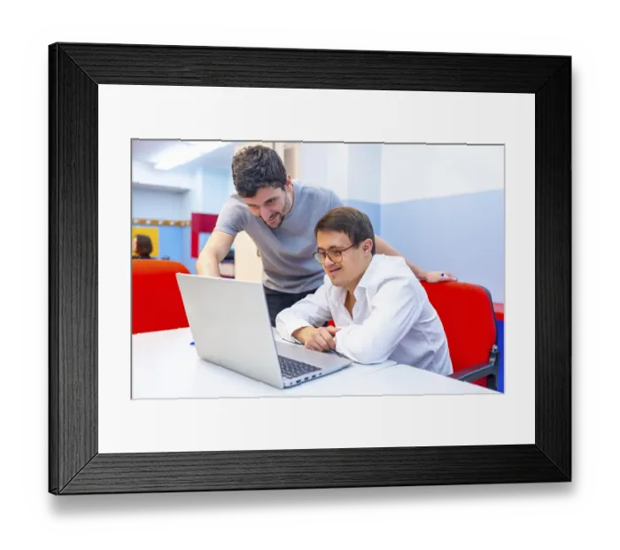 Framed Print : Friendly adult male teacher helping a man with down syndrome during computing class