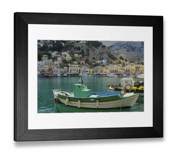Framed Print : Green and white fishing boat, in the background the houses of Symi Framed Print : Green and white fishing boat, in the background the houses of Symi