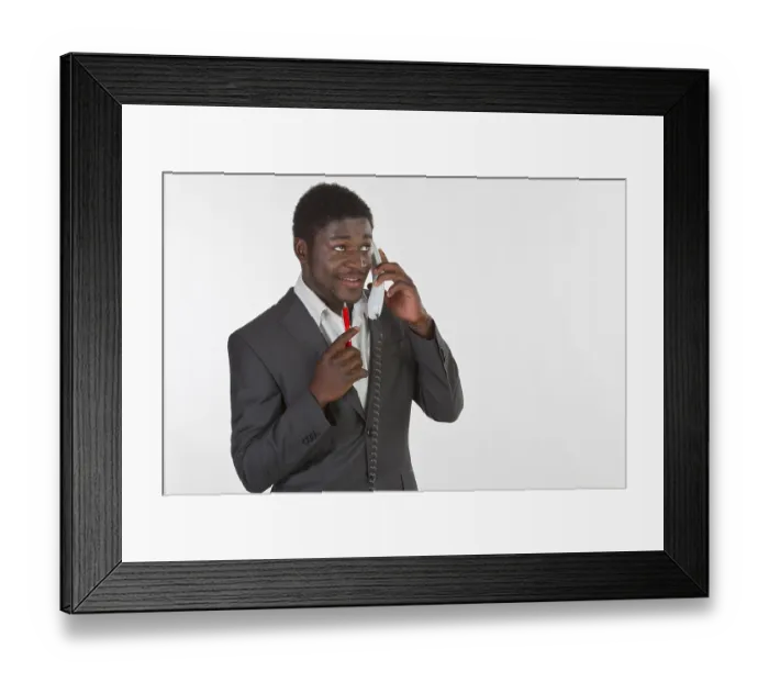 Framed Print : Young black man in a suit making a phone call in an office