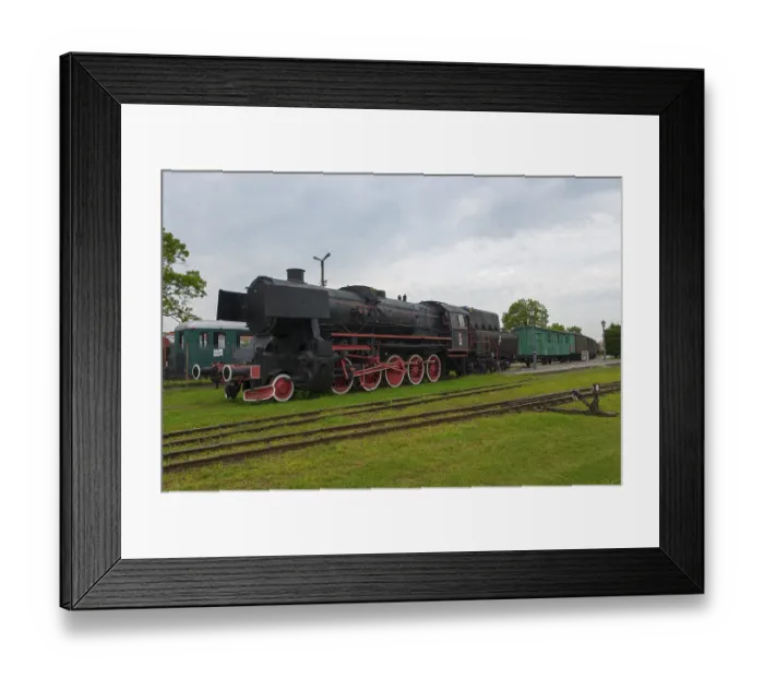 Framed Print : Historic steam locomotive with green wagons on a track under a cloudy sky