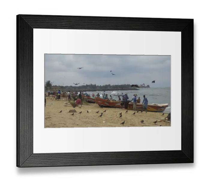 Framed Print : People and fishing boats on the beach with birds and clouds over the sea
