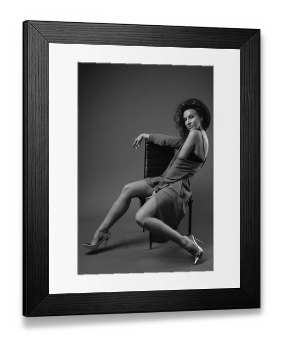 Framed Print : Studio shot of young beautiful woman with curly hair posing against gray background in black and white