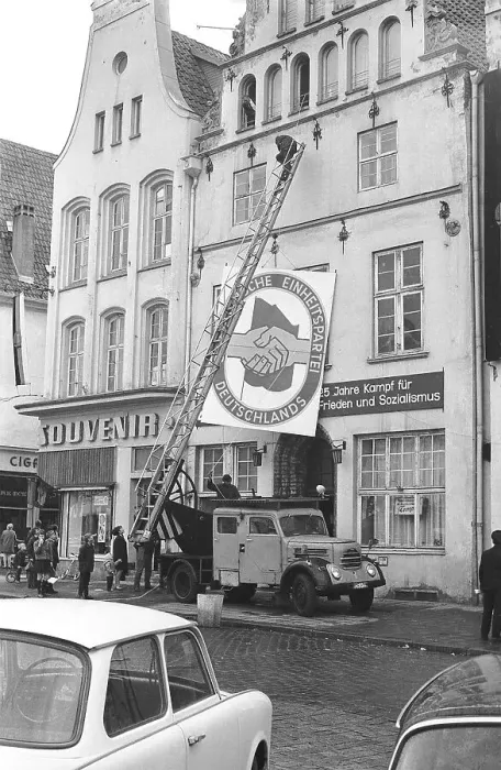 Framed Print : 13.04.1971, Rostock, Rostock district, hanging a poster in the shape of the SED party badge