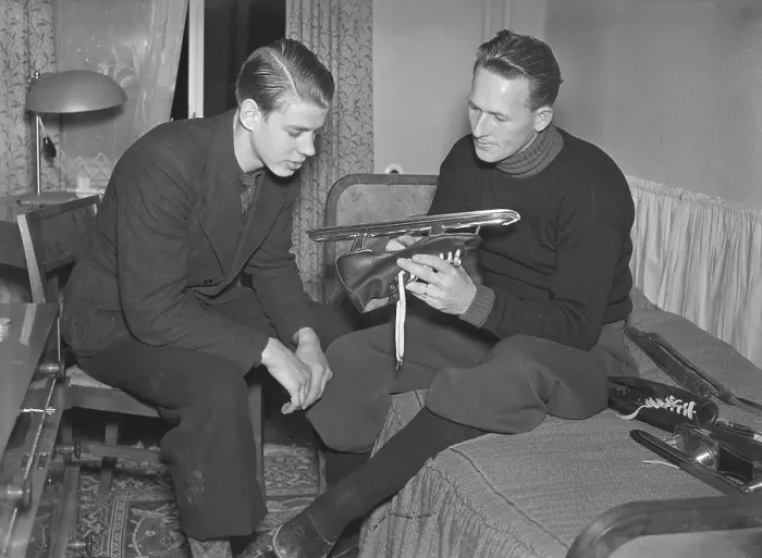 Framed Print : 1930s winter activities. Two men are sitting and discussing something regarding the skate he is holding