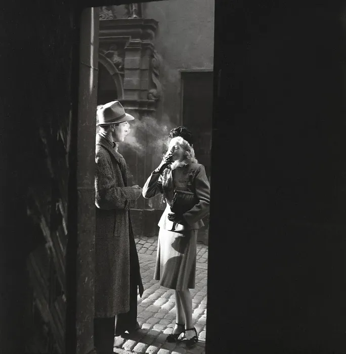 Framed Print : 1940s couple. A couple pictured in the evening sun in an old street smoking a cigarette