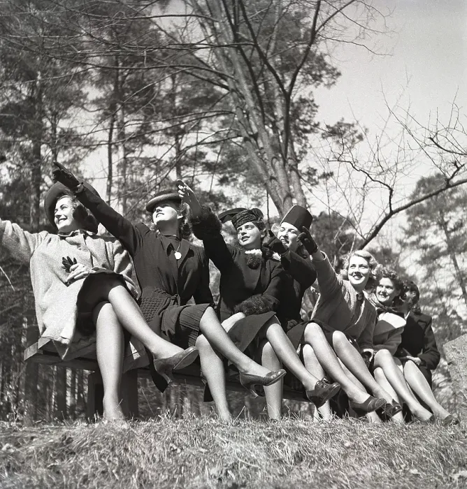 Framed Print : In the 1940s. A group of young people sitting together all points in one direction with their arms as if they want to