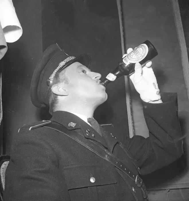 Framed Print : The 1940s. A man dressed in uniform drinks beer from a bottle made by the Danish brewery Tuborg