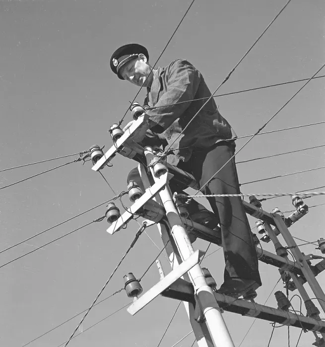 Framed Print : In the 1940s. A man is seen climbing on top of an electrical pole with power wires