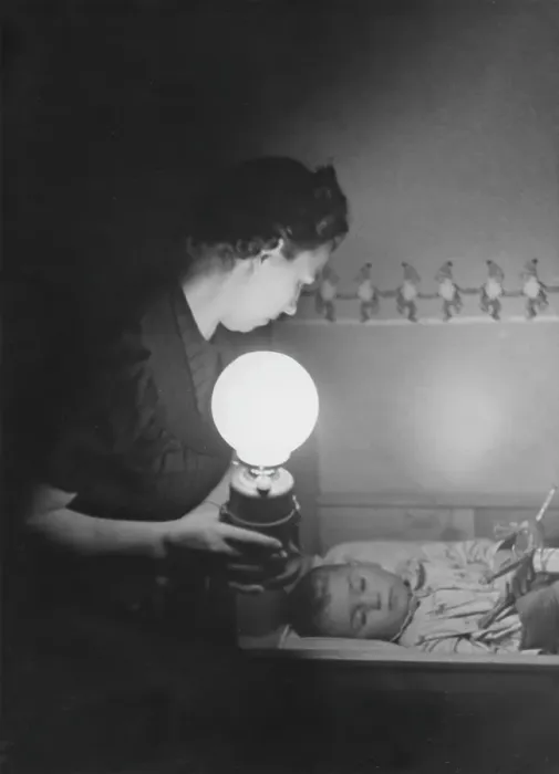 Framed Print : In the 1940s. An mother is in a room where her child is lying in a bed and sleeping