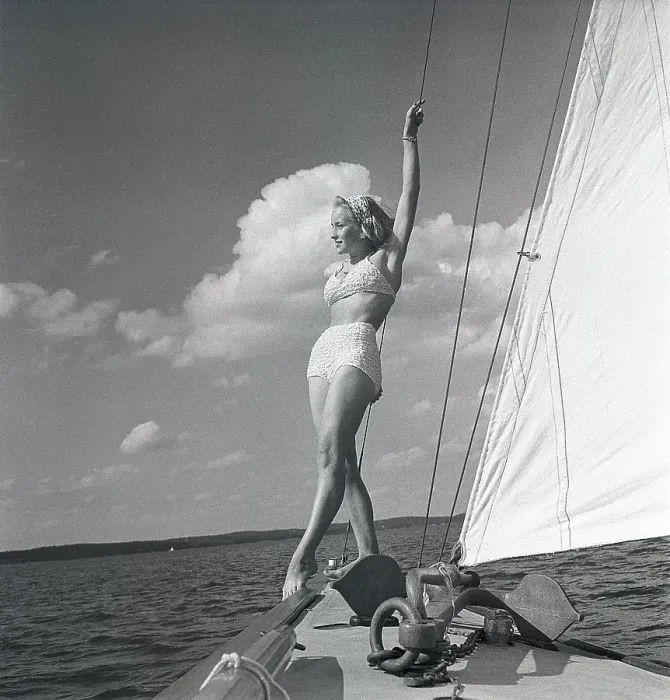Framed Print : 1940s sailing boat. A young woman is aboard a fashionable sailing boat and is standing on deck when it cruises forward with wind in the sails. She is wearing a typical 1940s two piece bathing suit. Sweden 1946 Photo Kristoffersson ref AC101-4
