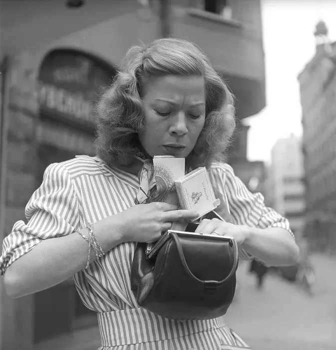 Framed Print : In the 1940s. A woman is seen looking through her purse and tries to find something