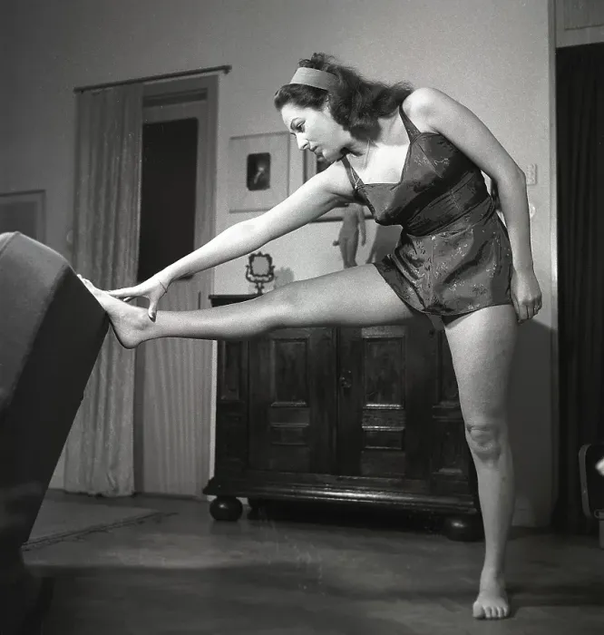 Framed Print : In the 1940s. A young woman in her livingroom while exercising Framed Print : In the 1940s. A young woman in her livingroom while exercising