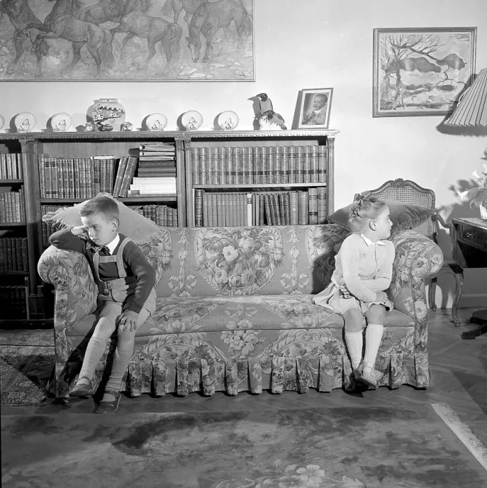 Framed Print : In the 1950s. Two children are sitting at the far ends of the sofa