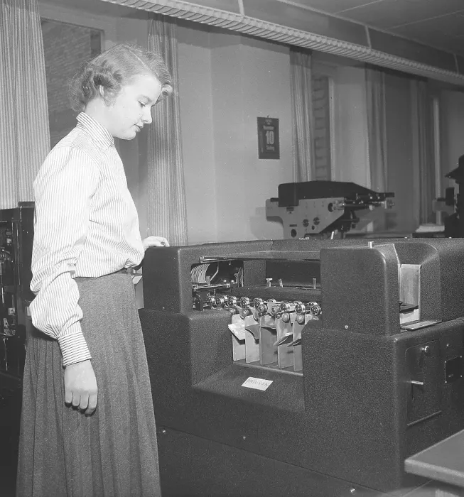 Framed Print : In the 1950s. A female clerk at punch card reader machine overlooking it's function