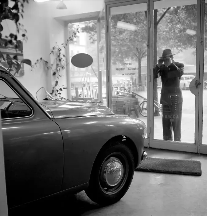 Framed Print : In the 1950s. A man is standing outside a store where an Alfa Romeo has caught is eyes