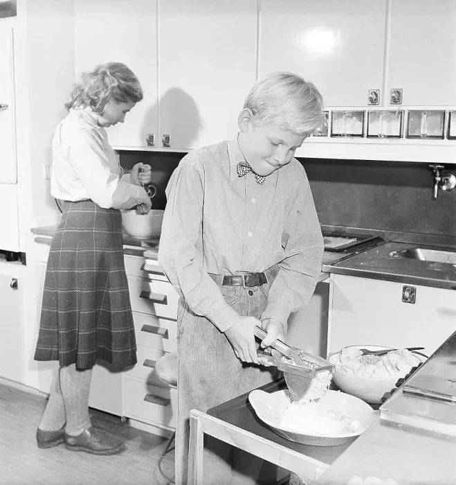 Framed Print : In the 1950s. A teenage boy and girl are cooking in the kitchen
