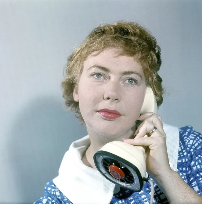 Framed Print : 1950s telephone. A young woman is talking on the telephone