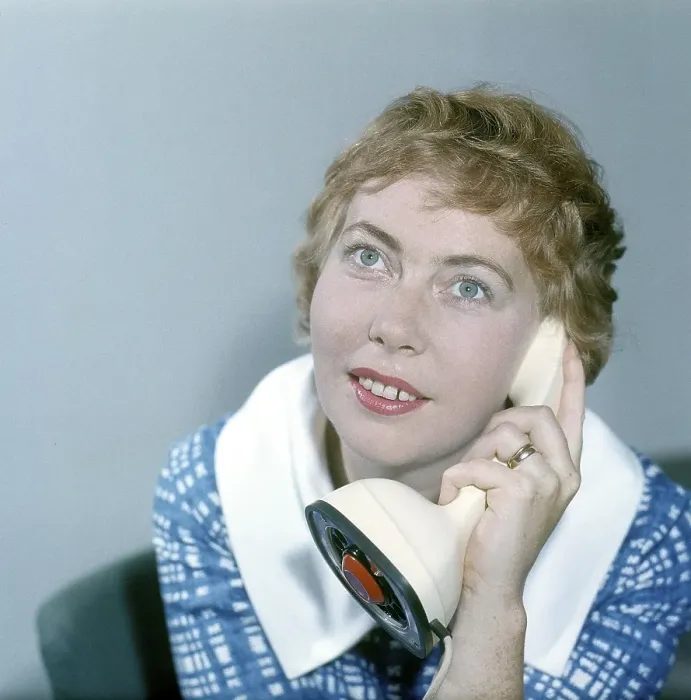 Framed Print : 1950s telephone. A young woman is talking on the telephone. A Swedish on-piece plastic telephone created by Ericsson Company of Sweden and launched 1956