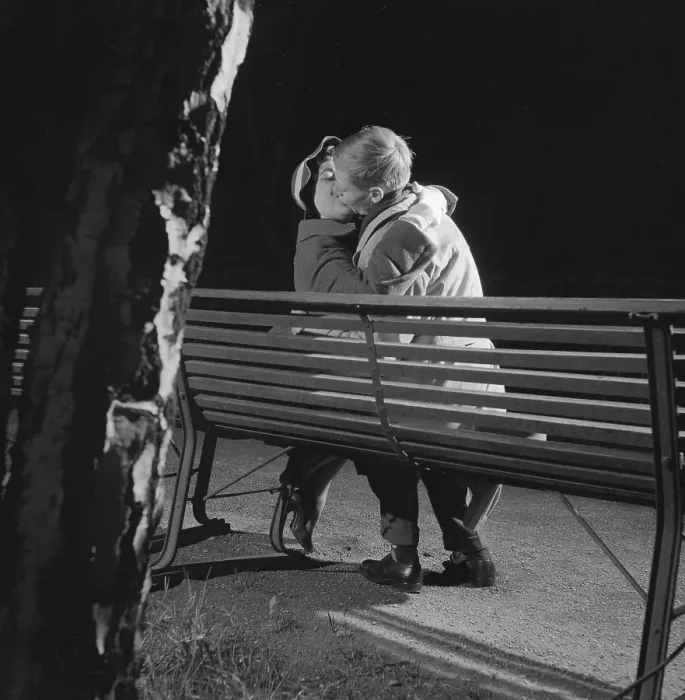 Framed Print : In the 1950s. A young couple is sitting on a bench kissing Framed Print : In the 1950s. A young couple is sitting on a bench kissing