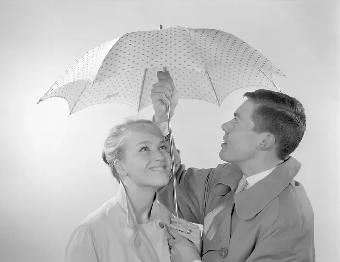 Framed Print : 1960s couple. A happy smiling couple is standing under an umbrella