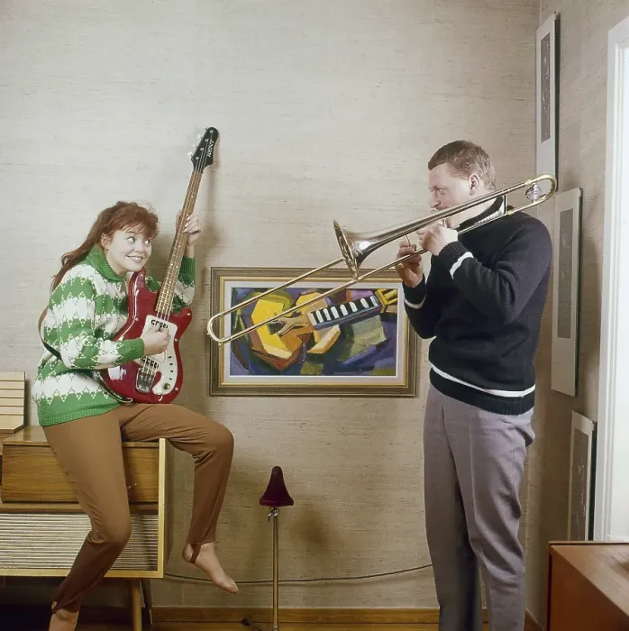 Framed Print : In the 1960s. A couple is seen playing the trombone and an electric guitar Framed Print : In the 1960s. A couple is seen playing the trombone and an electric guitar