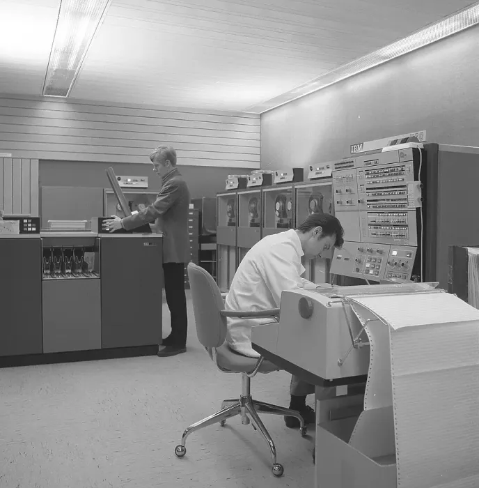 Framed Print : In the 1960s. Interior of a room with computers and people on the job of handling them and register and reading information. A sign above the mainframe computer says IBM 360 Framed Print : In the 1960s. Interior of a room with computers and people on the job of handling them and register and reading information. A sign above the mainframe computer says IBM 360
