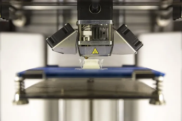 Framed Print : A 3D printer prints a white plastic detail