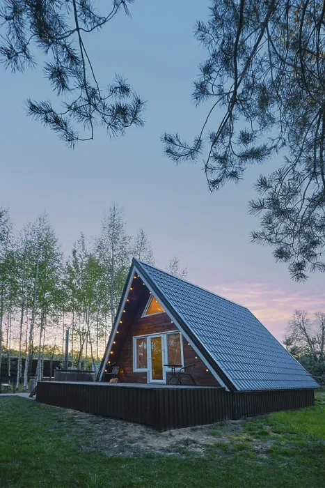 Framed Print : A-frame wooden cabin with light inside in early evening