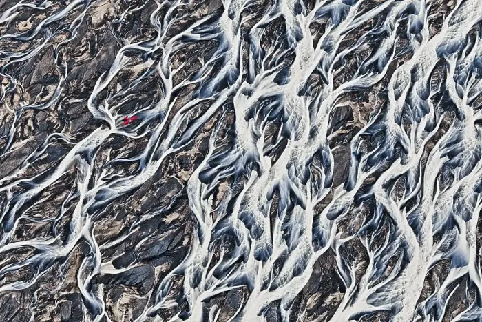 Framed Print : Aerial view, a red single-engine lightweight airplane flying over the flow structures of the melt water branching out