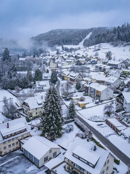 Framed Print : Aerial view of a snow-covered village surrounded by forests and mountains in winter Framed Print : Aerial view of a snow-covered village surrounded by forests and mountains in winter