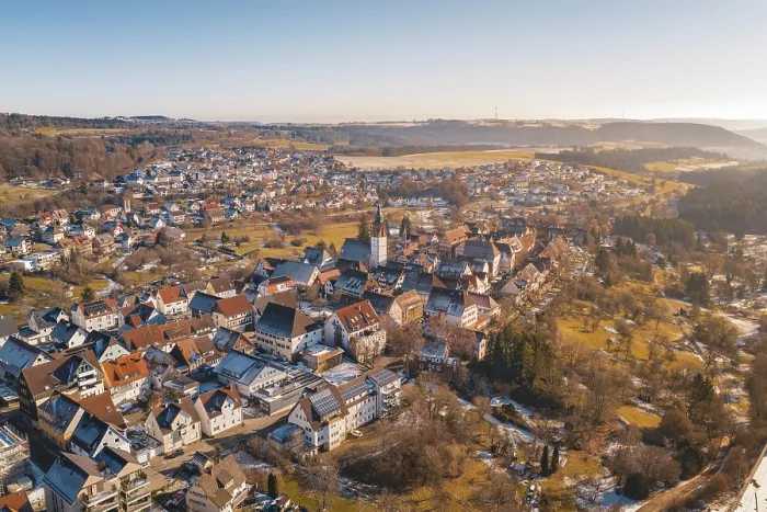 Framed Print : Aerial view of a town with a central church surrounded by red roofs and winter landscape under blue sky