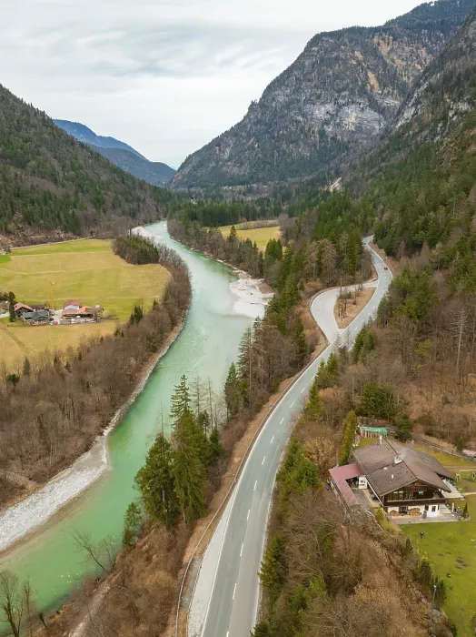 Framed Print : Aerial view of a winding Saalach river next to a road with surrounding forest and mountains under a cloudy sky