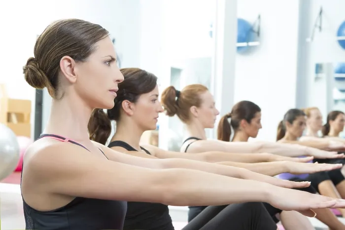 Framed Print : Aerobic Pilates personal trainer in a gym group class in a row
