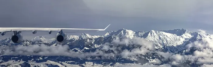 Framed Print : An aeroplane flies over a snow-covered mountain landscape and misty forests